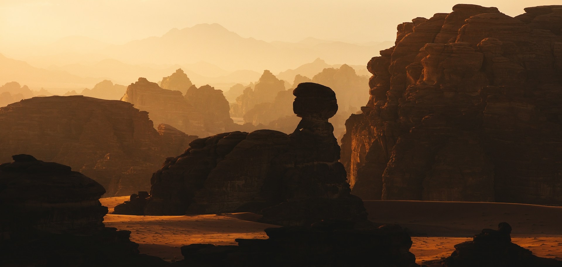 A cropped image of a rock formation in the desert with mountains in the background by NEOM from Unsplash.com